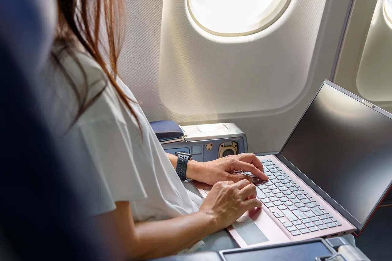 飛行機の中でPCで作業している様子