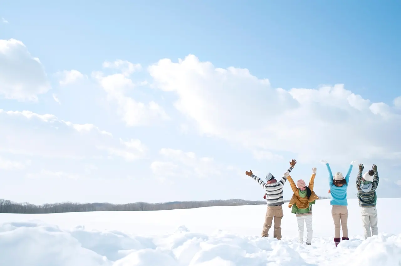 冬の雪原で万歳している男女４人